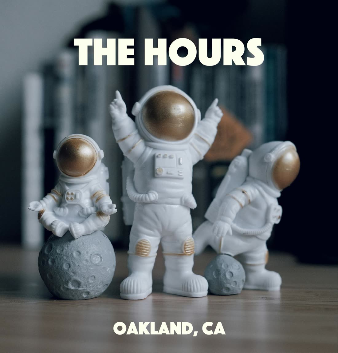 Three small astronaut figurines under the words The Hours, Oakland, CA.