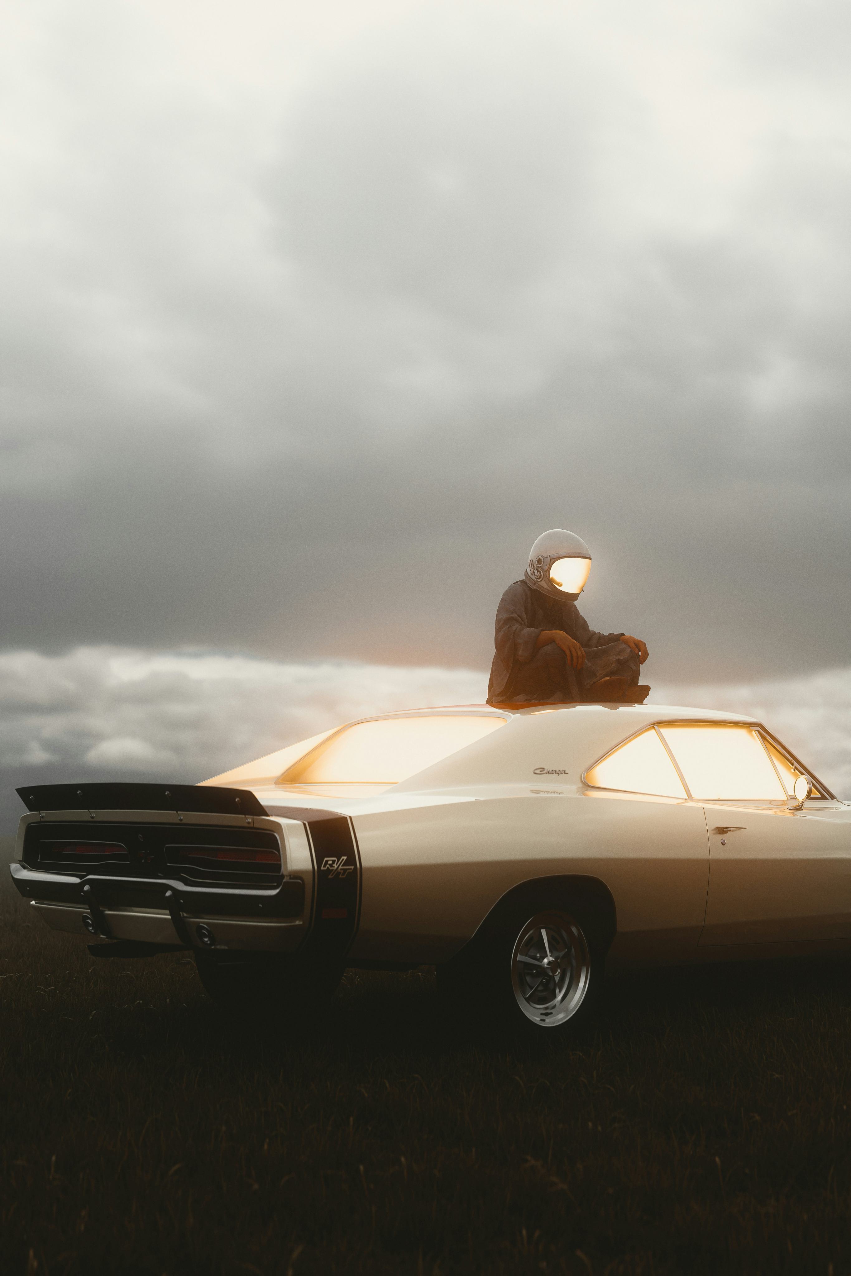 An astronaut sits on the roof of a vintage muscle car at dusk under heavy clouds.
